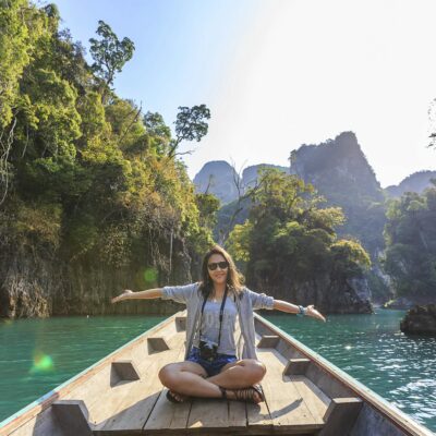 Asian woman relishing a serene boat journey through the lush karst landscape of Thailand's Khlong Sok.