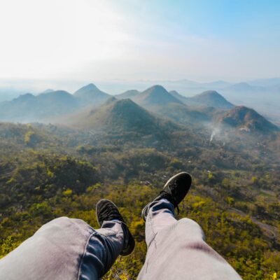 Feet dangling over the stunning landscape of Wonogiri Hills during sunrise, capturing the essence of Indonesian nature.